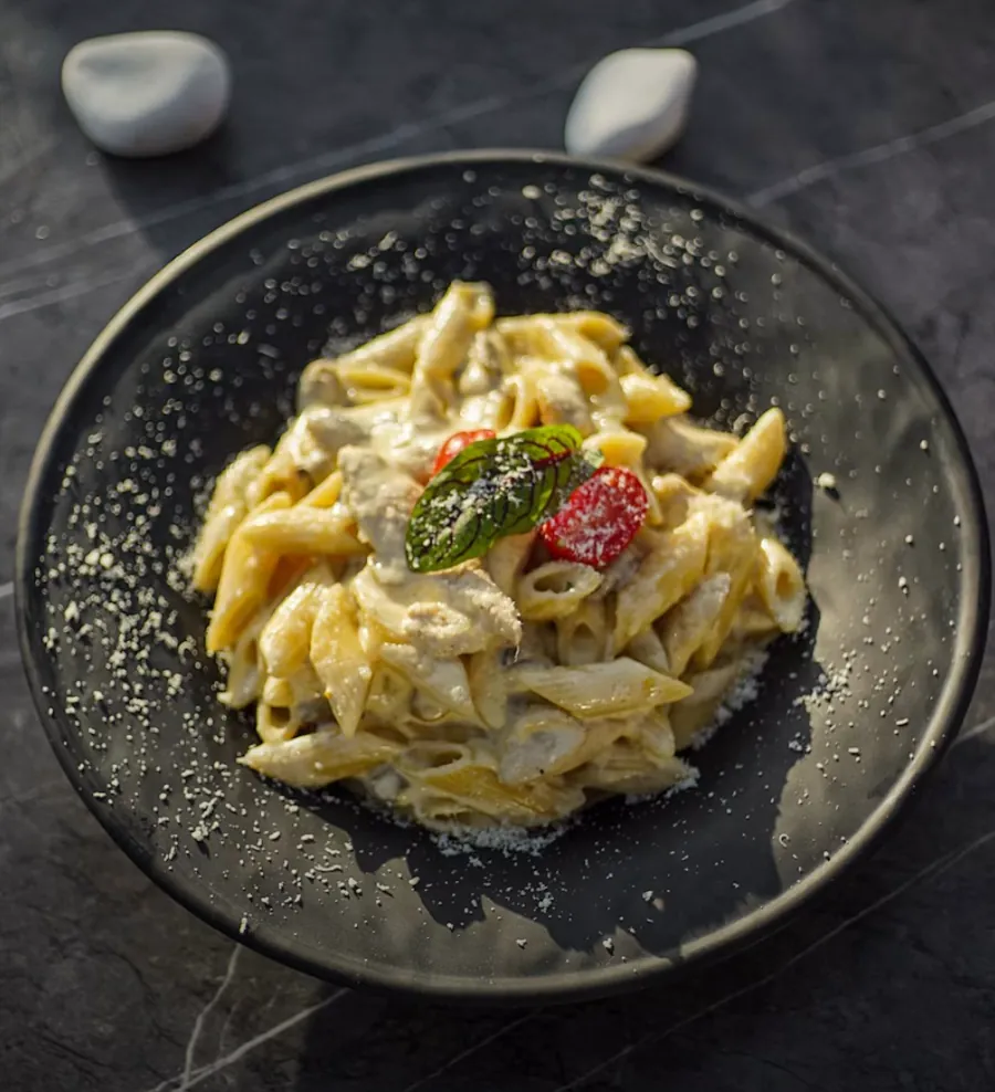 Cacio e pepe with basil and a roast tomato in a dark bowl, the photo on a sample Fork post.